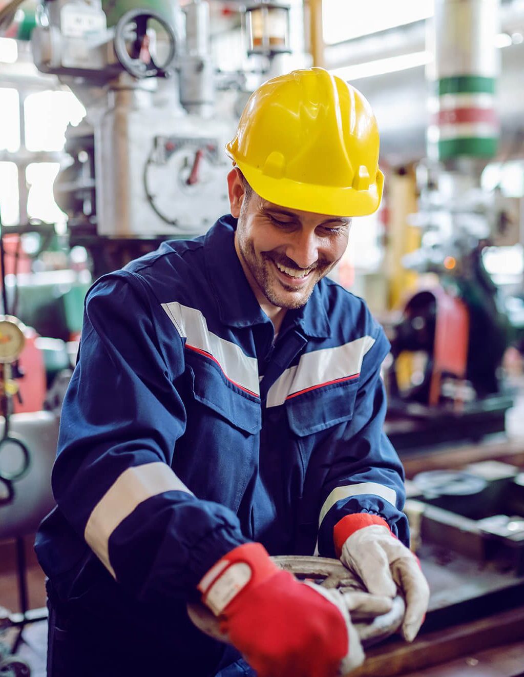 Smiling hardworking energy plant worker in working suit screwing valve