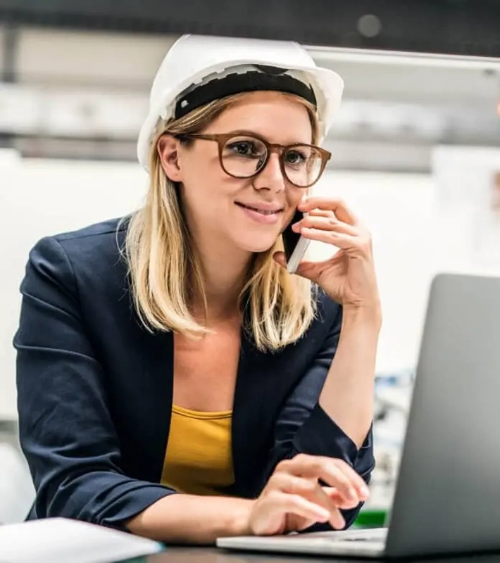 Female Plant Manager using laptop and talking on phone