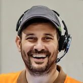 man with headset and orange shirt smiling